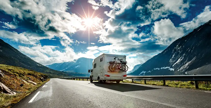 Wohnmobil von Hinten auf Bergstraße im Sonnenlicht