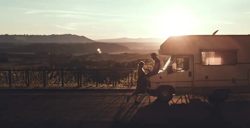 Pärchen vor Wohnmobil im Sonnenuntergang