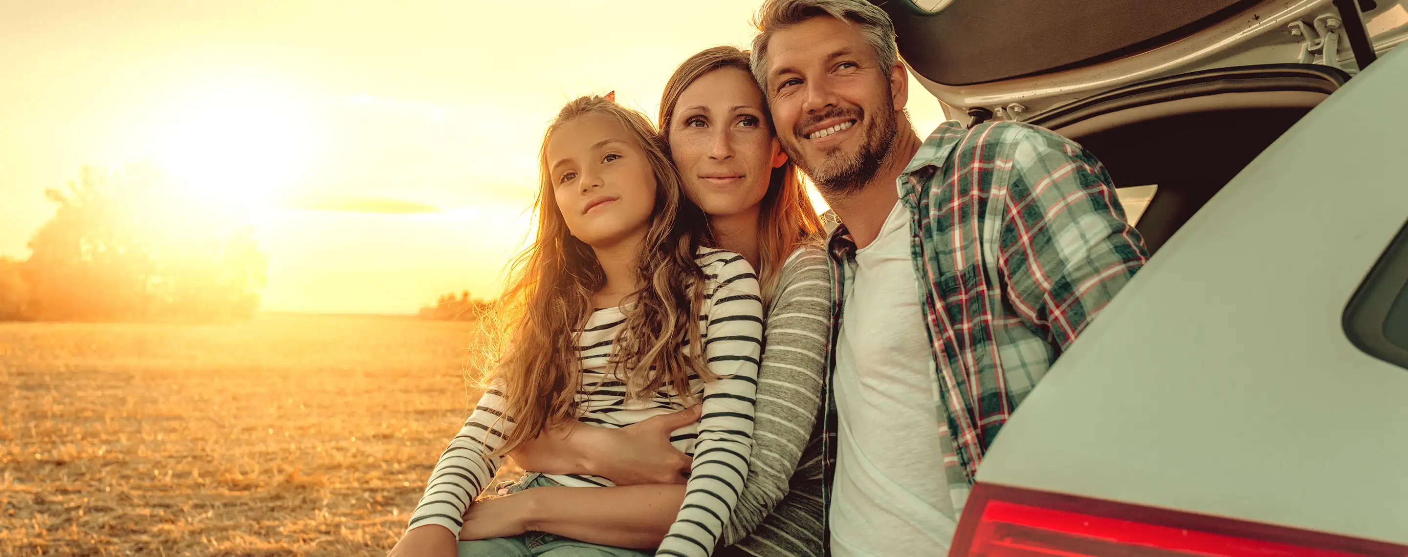 familie am kofferraum bei sonnenuntergang