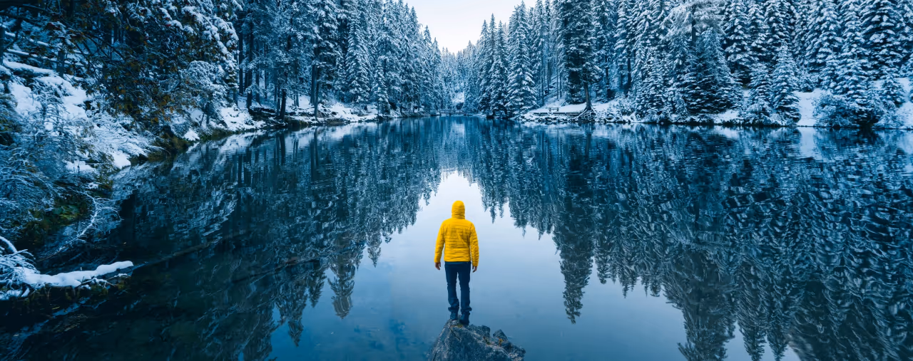 mann in gelber jacke am ufer eines sees im winter, hertz autovermietung