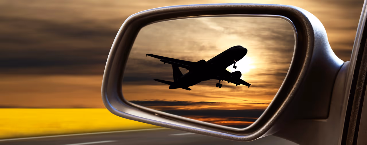 Flugzeug im Rückspiegel eines Mietwagens