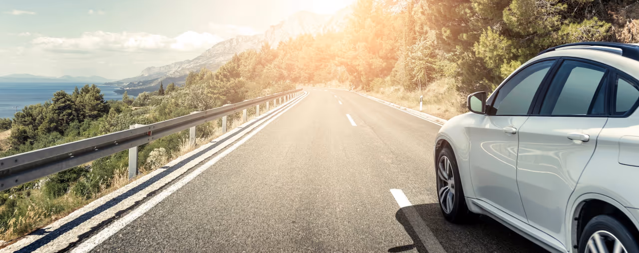 Weißer Mietwagen auf einer Küstenstraße