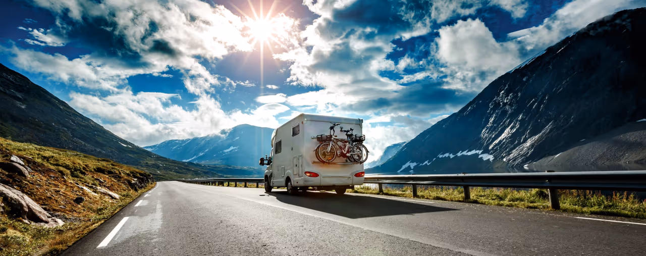 Wohnmobil von Hinten auf Bergstraße im Sonnenlicht