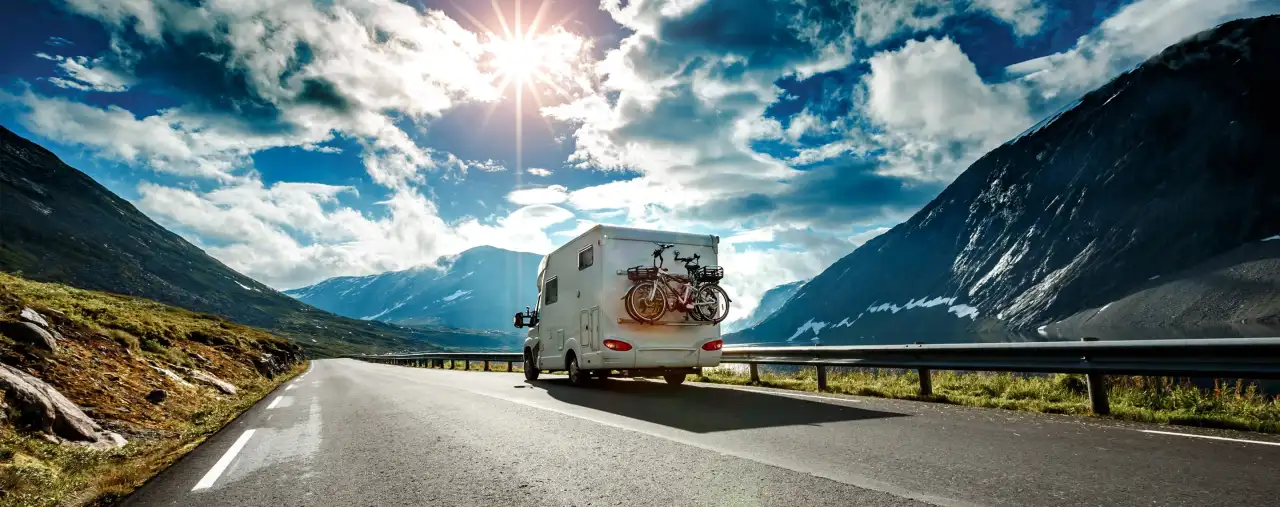 Wohnmobil von Hinten auf Bergstraße im Sonnenlicht