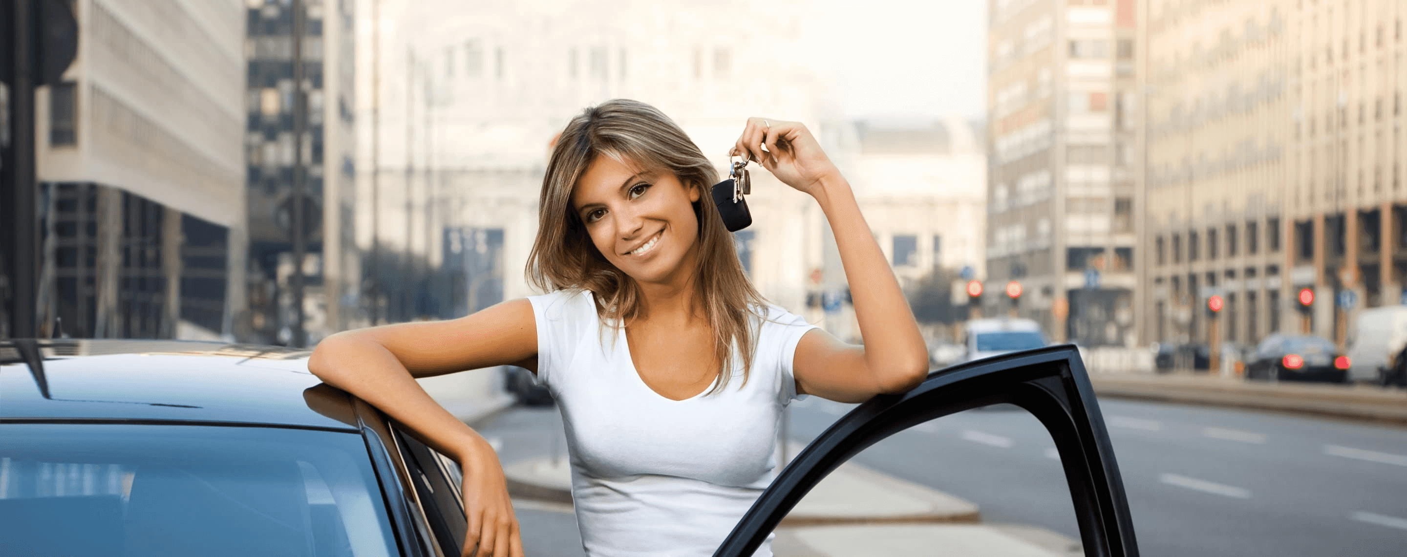Frau mit Autoschlüssel steht lächelnd neben Auto