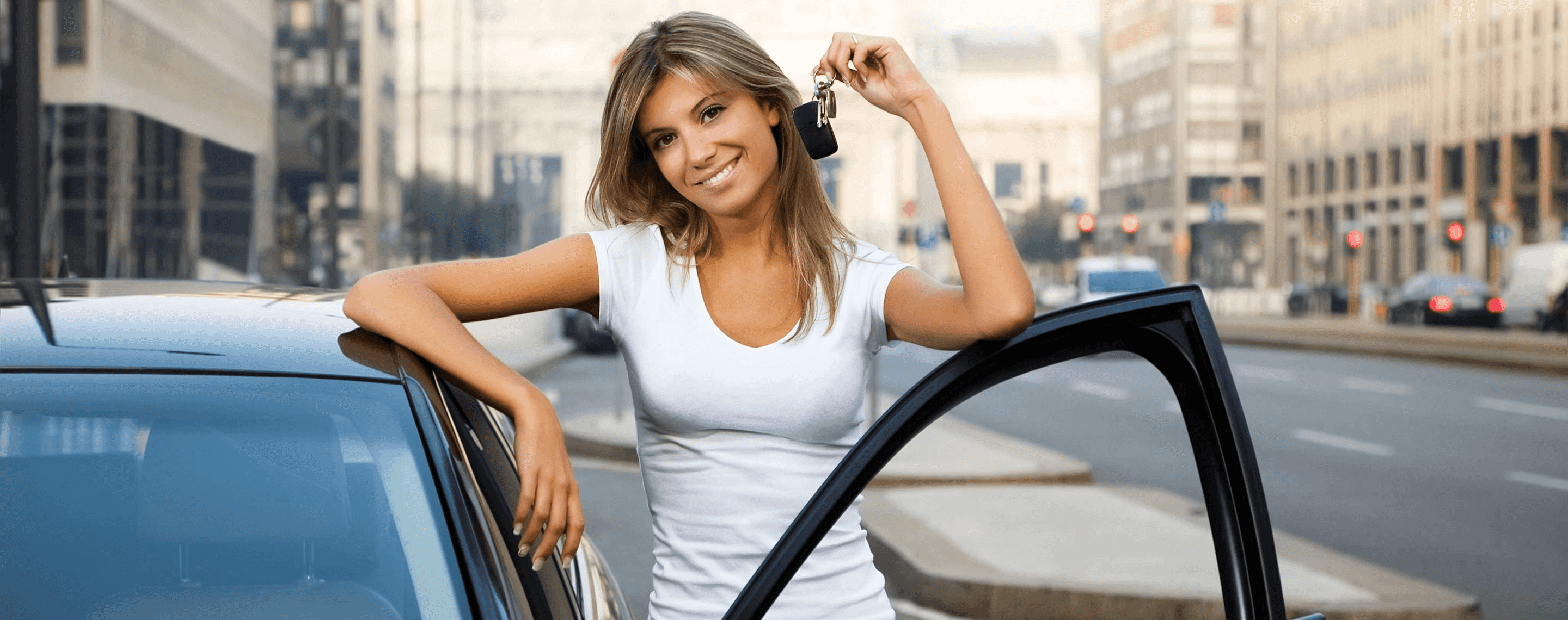 Frau mit Autoschlüssel steht lächelnd neben Auto
