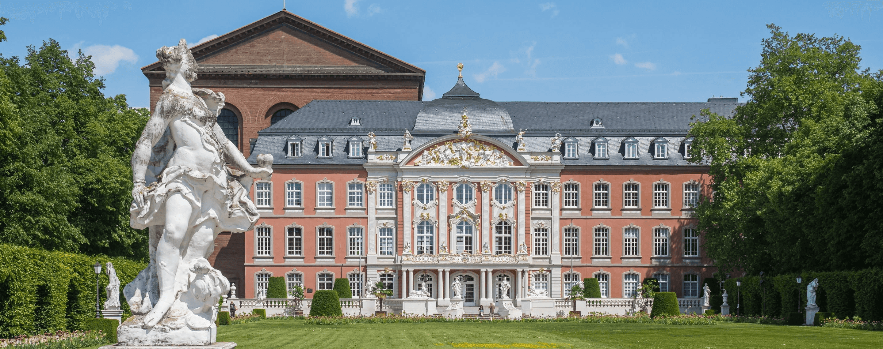 Universitätsgebäude in Trier mit Statue im Vordergrund