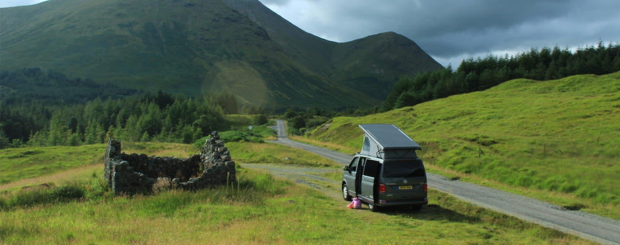 Campervan am Wegrand auf der Isle of Mull mit grüner Wiese und Berg im Hintergrund
